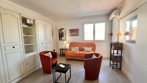 A living room with a sofa, two armchairs, a small table, and a cabinet. - Magellan (Cannes)
