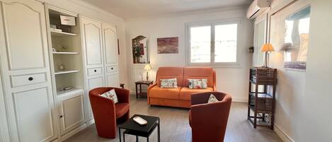 Ein Wohnzimmer mit einer Couch, zwei Sesseln, einem kleinen Tisch und einem Schrank.