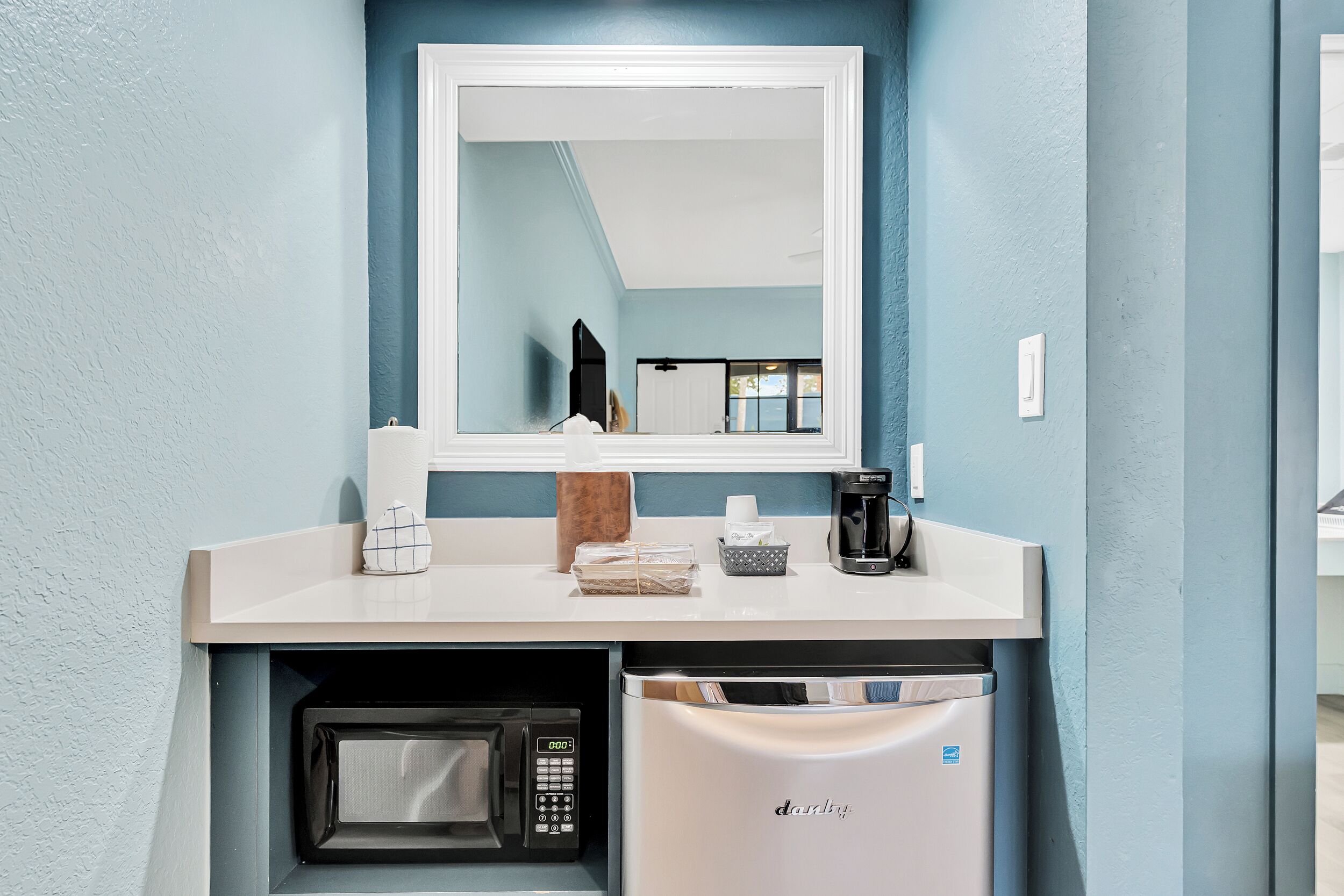 A compact kitchenette with a microwave, coffee maker, and a small refrigerator.