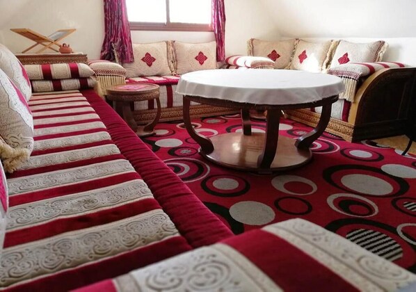 A traditional room with a sofa set, a round table, and patterned rugs.
