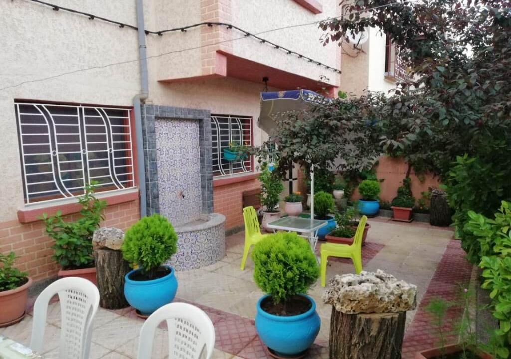 A courtyard with potted plants, outdoor furniture, and a tiled floor.