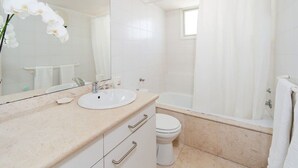 Een badkamer met een wastafel, spiegel, toilet en bad.