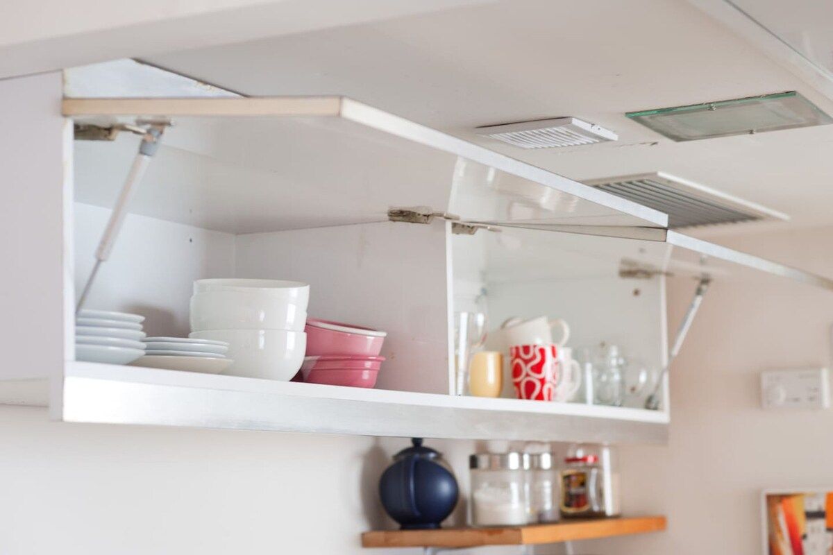 A kitchen with white cabinets, a blue pot, and various kitchen items on shelves.