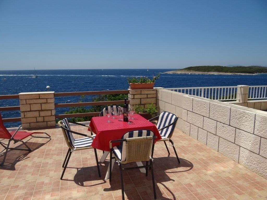 A terrace with a table and chairs, overlooking a body of water.