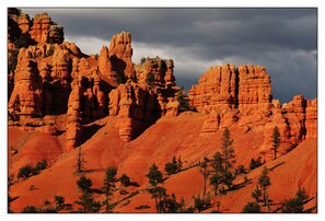 A rugged landscape with red rock formations and sparse trees.