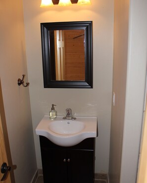 A bathroom with a white sink, a black cabinet, and a mirror above the sink.