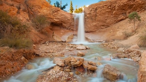 A waterfall in a rocky canyon with a clear stream below.