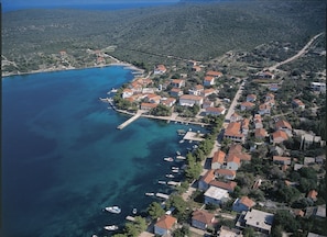 An aerial view of a coastal village with houses, a pier, and boats.