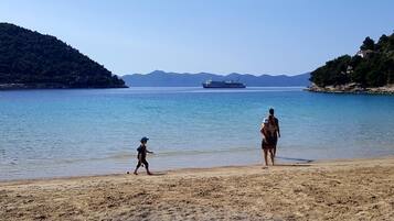 Enjoy a serene beach experience with calm waters and a distant cruise ship view.