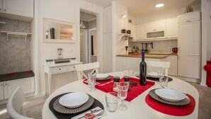 Uma cozinha moderna com armários brancos, uma mesa de jantar posta com pratos, copos e talheres.