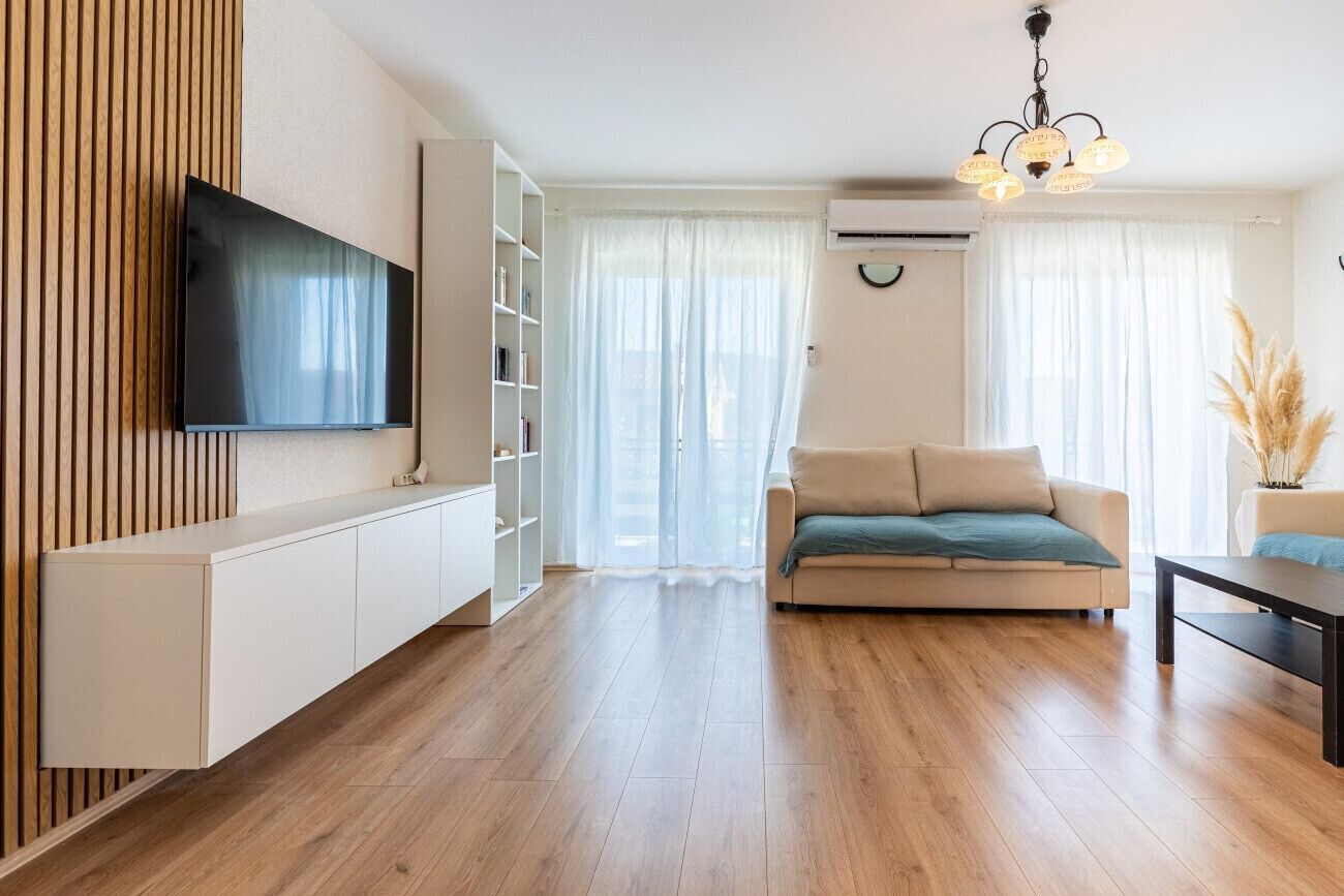 Una sala de estar moderna con un televisor de pantalla plana montado en la pared, un sofá, una mesa de centro y una estantería.