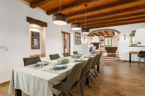 Un comedor con una larga mesa dispuesta para seis personas, vigas de madera en el techo y una pared de piedra al fondo.