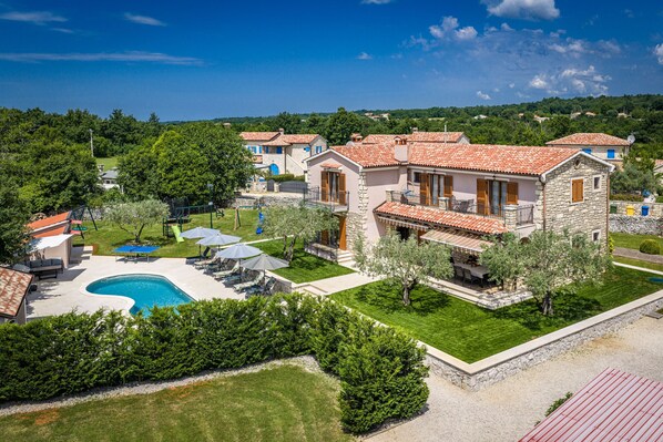 A villa with a swimming pool, outdoor furniture, and a well-maintained garden.