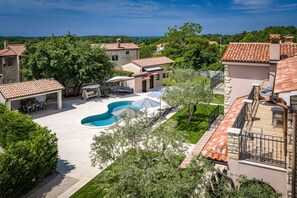 A residential property with a swimming pool, outdoor seating, and a view of the surrounding landscape.