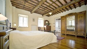 A bedroom with a large bed, wooden ceiling beams, a dresser, and a wardrobe. - Villa in San Gennaro with 6 bedrooms sleeps 11 (San Gennaro)
