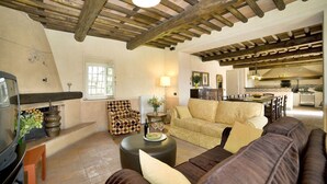 A spacious living room with a fireplace, a sofa set, a dining area, and a kitchen in the background. - Villa in San Gennaro with 6 bedrooms sleeps 11 (San Gennaro)