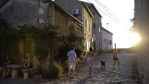 Una calle adoquinada con edificios de piedra, un banco y gente caminando.