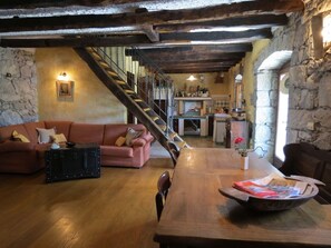 A rustic interior with a wooden dining table, a sofa, and a staircase leading to a kitchen area. - Holiday Home in Roč with Terrace, Air condition, WIFI, Washing machine (3458-1) (Roc)