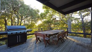 An outdoor deck with a grill, a wooden table, and chairs. - Edith's House (Fairhaven)
