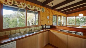 A kitchen with wooden cabinets, a sink, a toaster, and a clock on the wall. - Edith's House (Fairhaven)