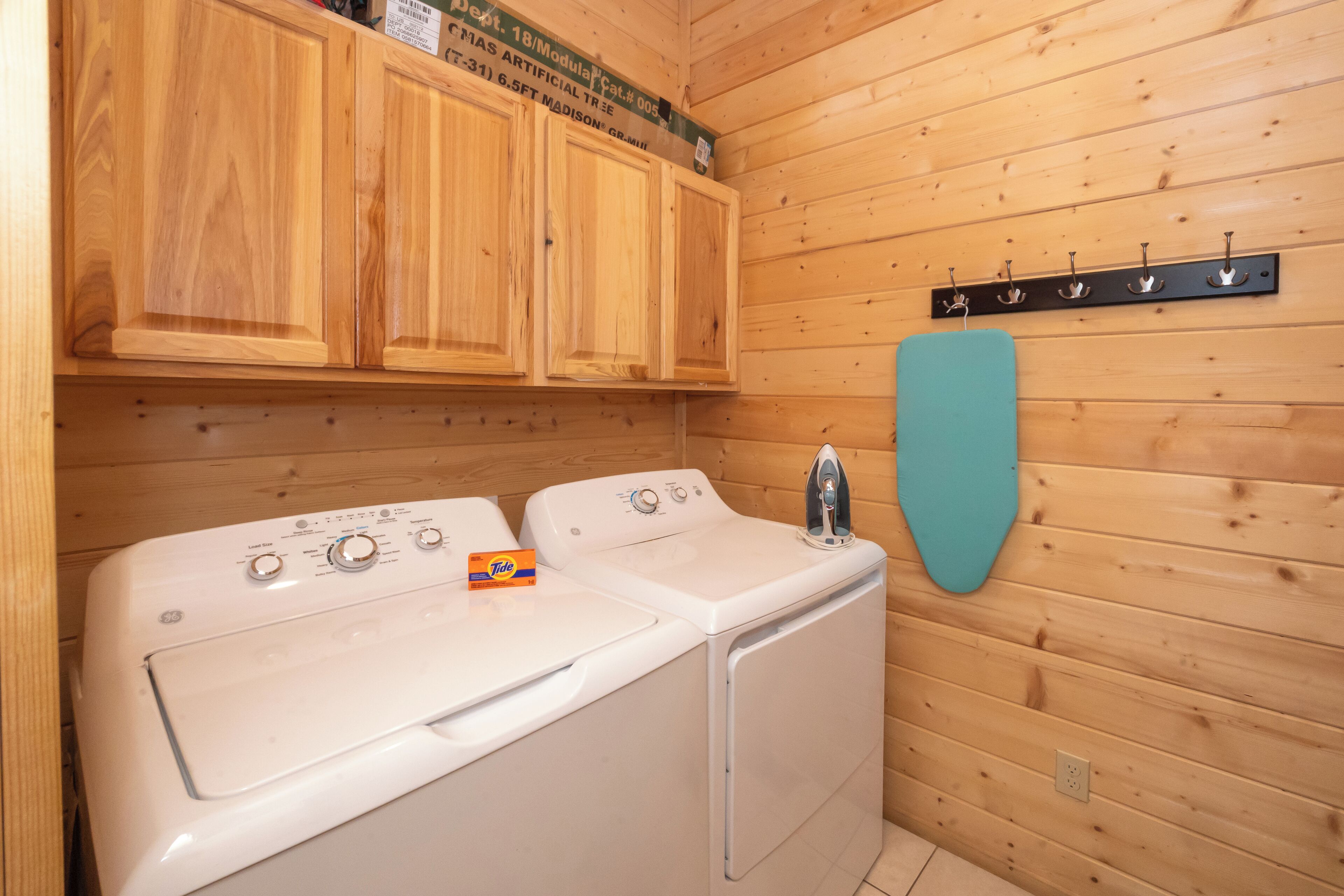 A laundry area with two washing machines, wooden cabinets, and a wall-mounted drying rack.