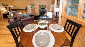 A wooden dining table set with plates, a bowl of fruit, and glasses. - Private Cabin, FREE Pool Access, Putt Putt, Fishing, Tennis, Golf, Basketball (Sevierville)