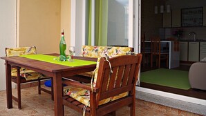 A wooden dining table with a green tablecloth, two chairs with floral upholstery, and a bottle of green liquid. - Apartment in Poljana with Seaview, Terrace, Air condition, WIFI (3617-5) (Poljana)