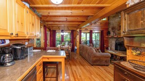 Interior de una cabaña de madera con cocina, comedor y sala de estar.