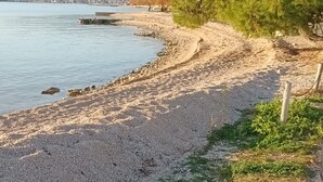 A pebble beach with a view of a city in the distance. - Apartment in Vodice with Seaview, Terrace, Air condition, WIFI (3420-3) (Vodice)