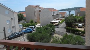A residential area with buildings, parked cars, and a view of a body of water. - Apartment in Vodice with Seaview, Terrace, Air condition, WIFI (3420-3) (Vodice)