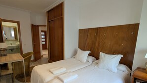 A double bed with white linens, a wooden headboard, and a bedside table with a lamp. - 293 - Apartamento El Puerto (Tarifa)