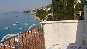 Parveke, jolta avautuu näkymä merelle, laatoitettu lattia ja pöytä, jonka päällä on kuvioitu pöytäliina.