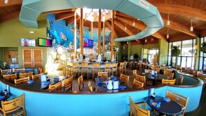 Un restaurant doté d’un bar incurvé, de chaises en bois et d’une grande fresque représentant des poissons sur le mur.
