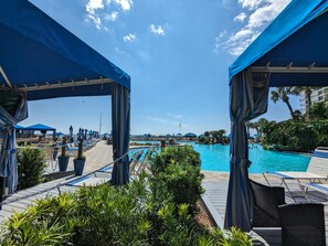 A poolside area with lounge chairs and umbrellas, a clear blue sky, and a view of the pool.