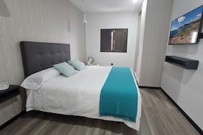 Une chambre à coucher moderne, avec un lit, une table de chevet, une commode, une fenêtre et un téléviseur fixé au mur.