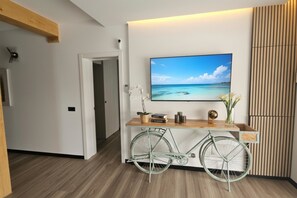 Ein modernes Wohnzimmer mit einem Wandfernseher, einem Fahrrad und einem Holzkonsolentisch.