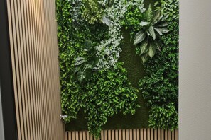 A wall with a vertical wooden slat design and a lush green wall with various plants.