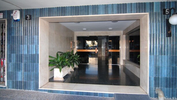 L'ingresso di un hotel con pavimento piastrellato, una reception e una scala che conduce ai piani superiori.