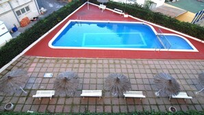 Una piscina sul tetto con bordo rosso, circondata da poltrone a sdraio e ombrelloni.
