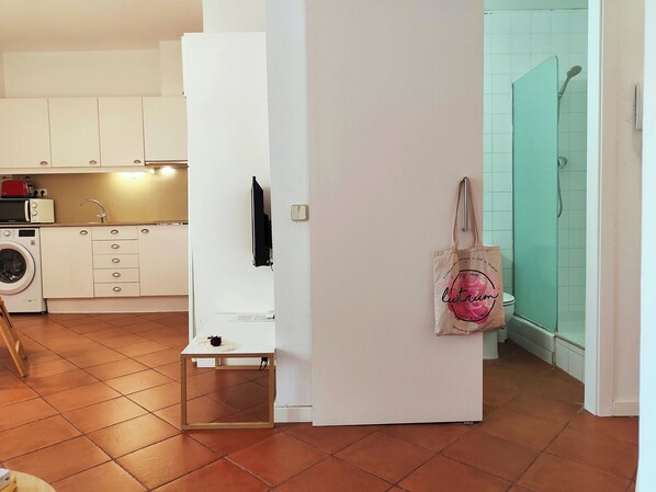 A compact kitchen with a washing machine, a microwave, and a small table.