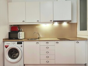Una piccola cucina accessoriata con forno a microonde, tostapane, lavello e lavatrice.