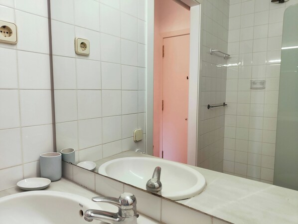 A bathroom with a white sink, a mirror, and a shower area.