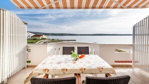 En terrasse med et bord og stole, havudsigt og et hvidt hegn.