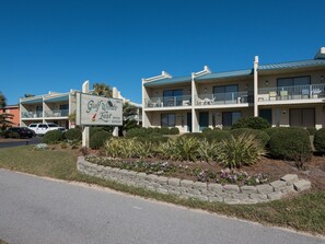 Un motel con un letrero que dice 'Gulf Winds East Office' y un muro de piedra con flores.