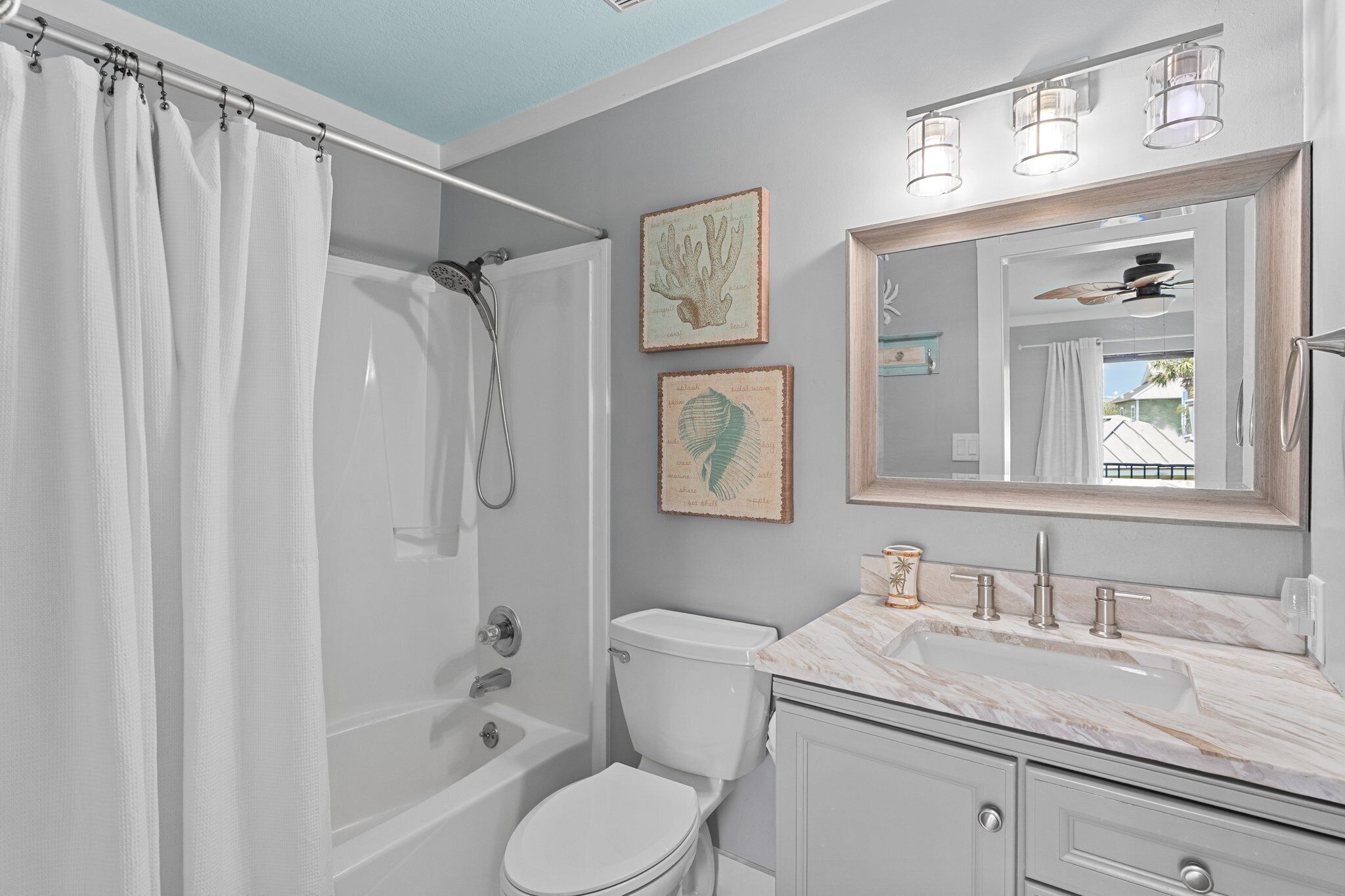 A bathroom with a bathtub, toilet, and sink. There are two framed pictures on the wall.
