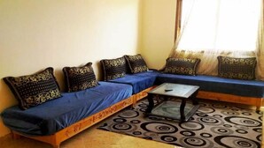 Un salon avec un canapé bleu, des coussins à motifs, une table basse et un tapis à motifs.