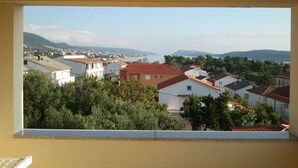 A view from a window overlooking a residential area with houses, trees, and distant hills. - Apartment in Banjol with Seaview, Balcony, Air condition, WIFI (605-3) (Banjol)