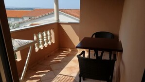 A balcony with a table and chair, a white balustrade, and a view of red-roofed buildings. - Apartment in Banjol with Seaview, Balcony, Air condition, WIFI (605-3) (Banjol)