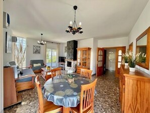 A spacious living area with a dining table, sofas, and a fireplace.