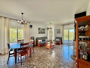 A spacious living area with a dining table, sofas, and a large wooden cabinet.
